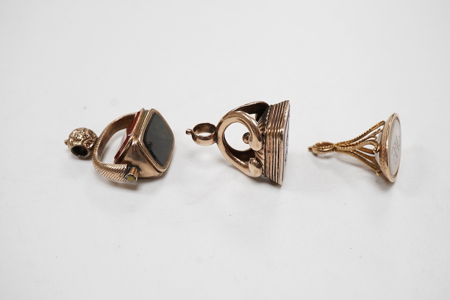 Three assorted 19th century yellow metal over laid fob seals, to include spinning set with three chalcedony stones, oval with white chalcedony carved with initials and rectangular with carnelian varved with a crest, larg